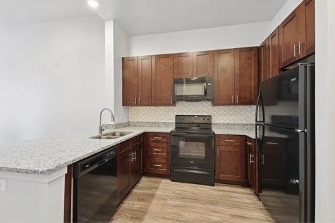 A kitchen with dark wood cabinets and black appliances.