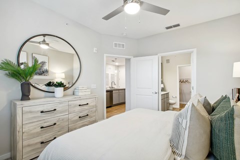 A bedroom with a large bed, a dresser, and a mirror.