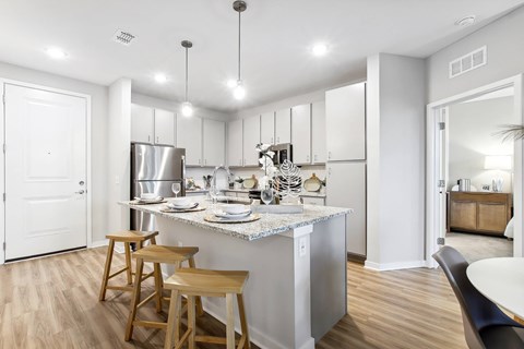 A kitchen with a white counter top and wooden bar stools.