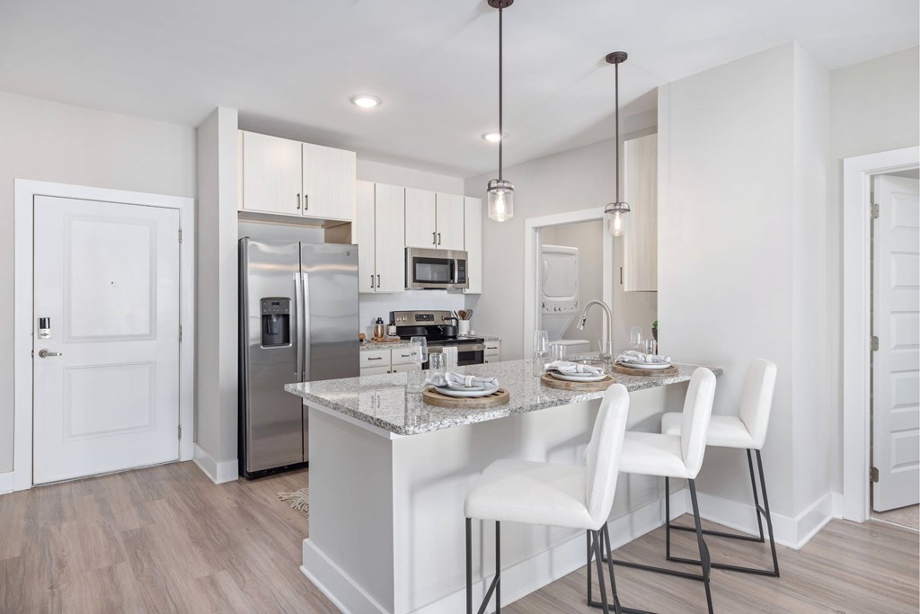 A kitchen with a white island and white chairs.