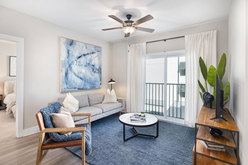 A living room with a sofa, a chair, a coffee table, a television, and a painting on the wall.