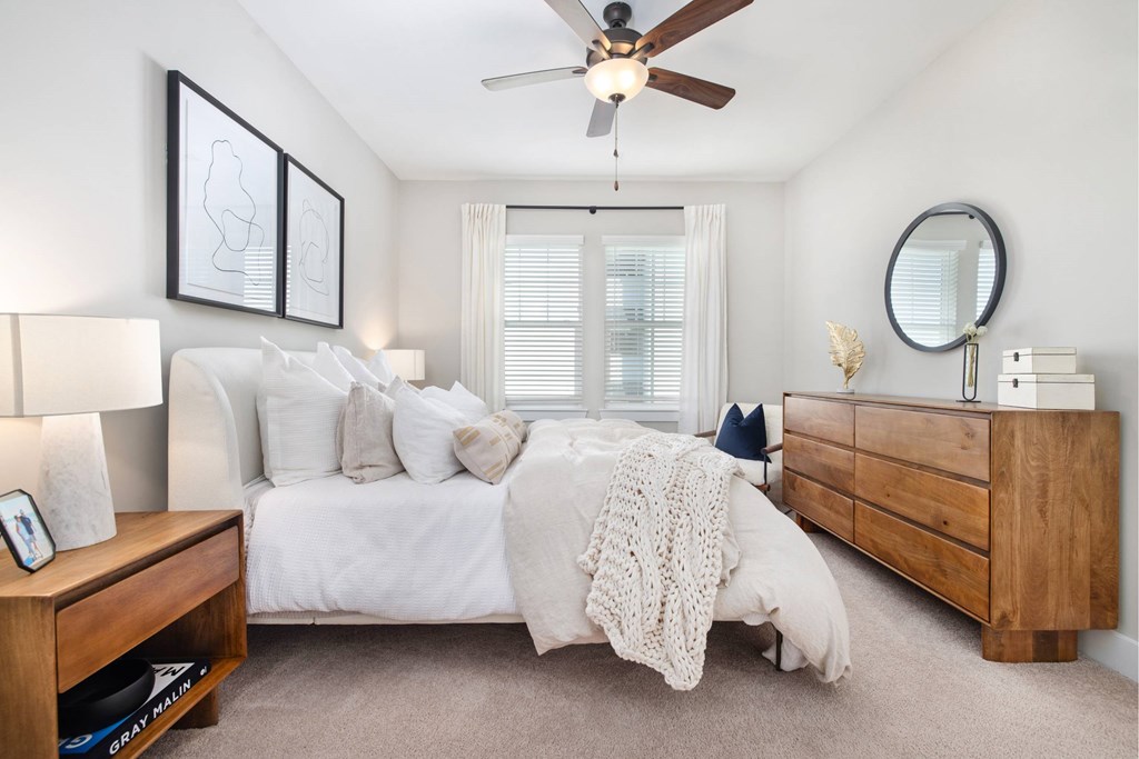 A bedroom with a bed, dresser, and ceiling fan.