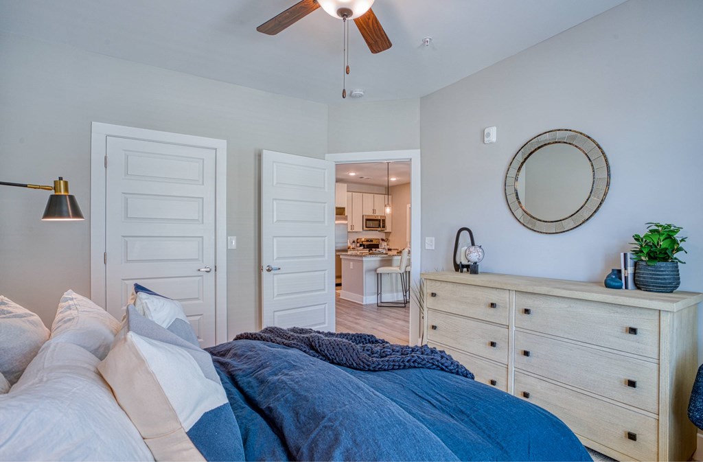 A bedroom with a bed, dresser, mirror, and ceiling fan.