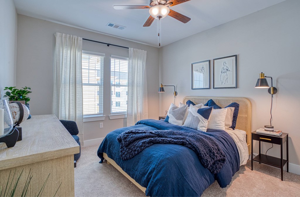 A bedroom with a bed covered in a blue blanket and pillows.