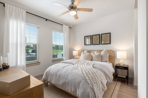 A bedroom with a large bed and a ceiling fan.