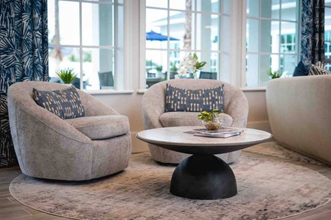 A living room with two grey armchairs and a round table with a plant on it.