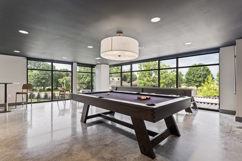 A pool table is in the middle of a room with a concrete floor and ceiling.