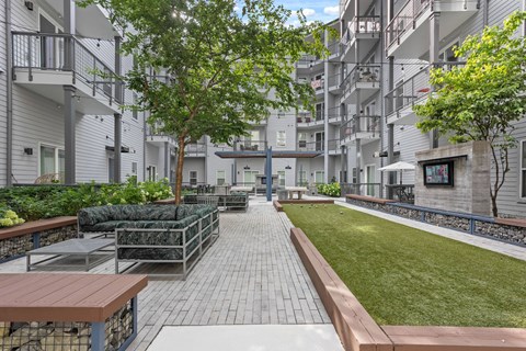 Apartment complex with a grassy area and benches.