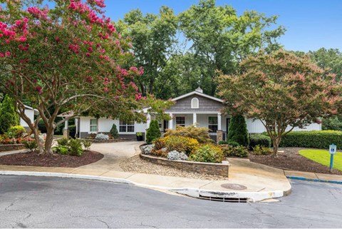 A house with a white picket fence and a driveway in front.