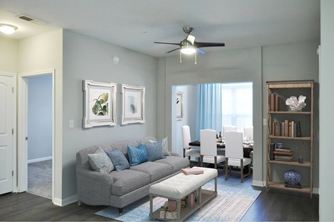 A living room with a grey couch and a ceiling fan.