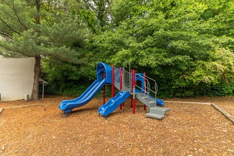 A playground with a blue slide and red railings.