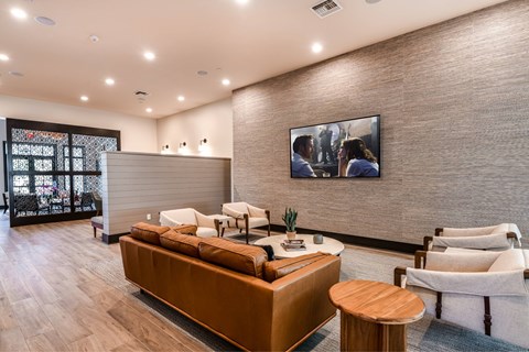 A modern living room with a brown sofa and a painting on the wall.