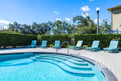 A swimming pool with blue water and lounge chairs.