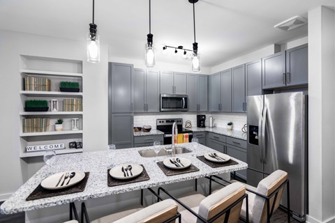 A modern kitchen with a dining table set for two.