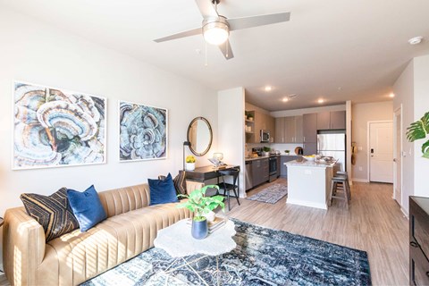 A living room with a beige couch and a ceiling fan.