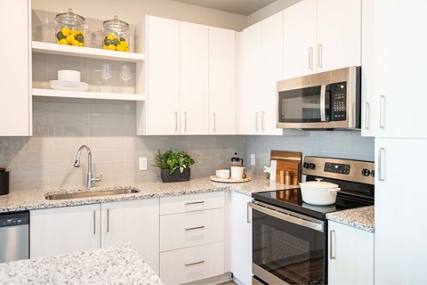 A kitchen with white cabinets and a black microwave.