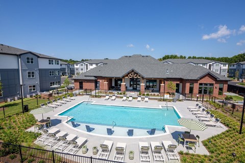 A large swimming pool surrounded by lounge chairs and a building in the background.