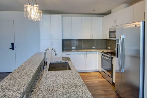 A kitchen with a granite counter top and stainless steel appliances.