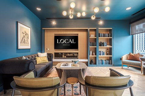 A living room with a black couch, a coffee table, and a bookshelf with the word LOCAL on it.
