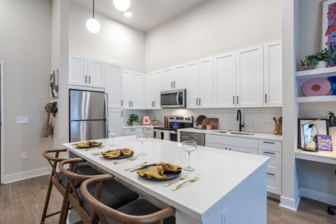 A kitchen with a table set for two with a white counter top.