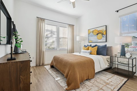 A bedroom with a bed, a dresser, and a ceiling fan.