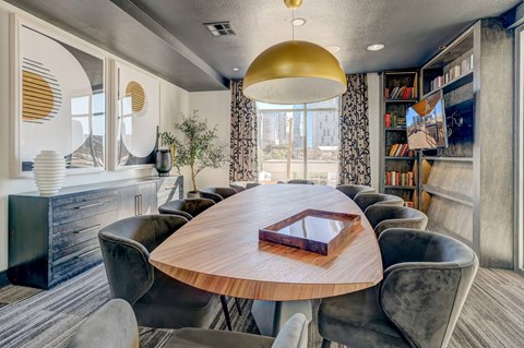 A modern dining room with a round wooden table and grey chairs.