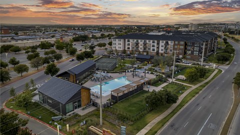 A sunset view of a road with a building and a pool.