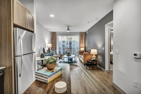 A modern kitchen with a refrigerator, a dining table with chairs, and a living area with a couch.