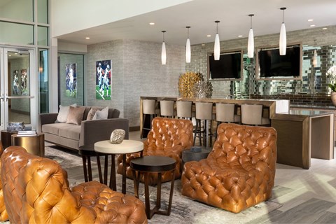 A living room with brown leather chairs and a grey couch.