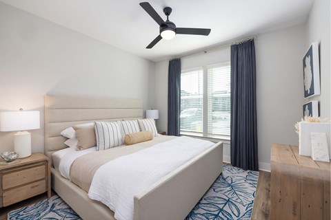 A bedroom with a large bed and a ceiling fan.