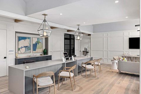 A modern kitchen with a grey counter and wooden chairs.