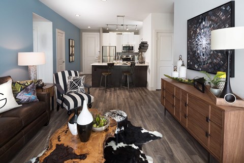 A living room with a cowhide rug and a black and white striped chair.