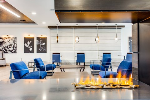 A modern living room with blue chairs and a fireplace.