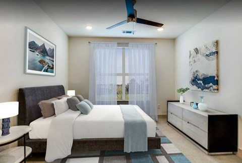 A bedroom with a bed, nightstand, and a ceiling fan.