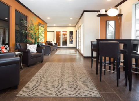 A living room with a rug on the floor and a dining table with chairs.