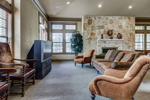 A living room with a stone fireplace and a brown chair.