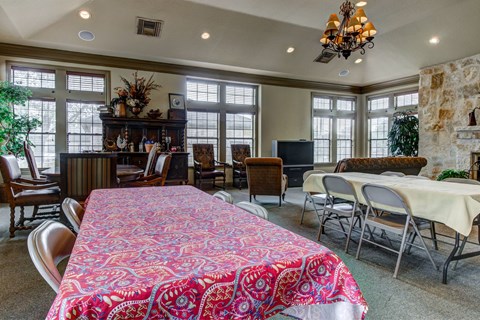 A dining room with a table covered in a red and pink tablecloth.