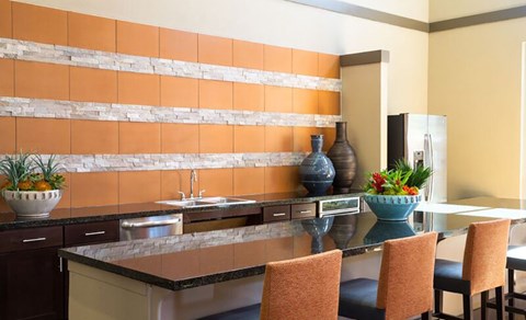 A kitchen with a counter and chairs.
