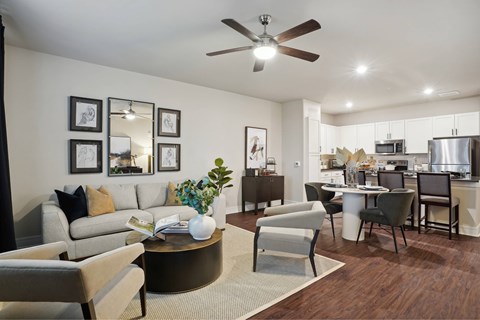 A living room with a grey couch and a coffee table with a vase of flowers on it.