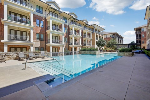 A swimming pool is surrounded by apartment buildings.