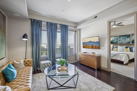 A living room with a brown sofa, a glass coffee table, and a painting on the wall.