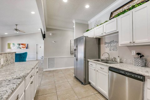 A kitchen with a stainless steel refrigerator and white cabinets.