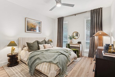 A bedroom with a large bed and a ceiling fan.