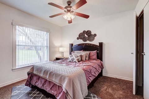 A bedroom with a bed, pillows, and a ceiling fan.