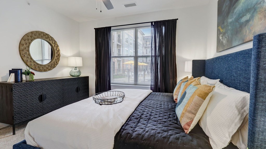 A bedroom with a black bed and a round mirror on the dresser. A bedroom with a black bed and a round mirror on the dresser.