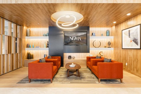 A modern living room with orange couches and a wooden ceiling.