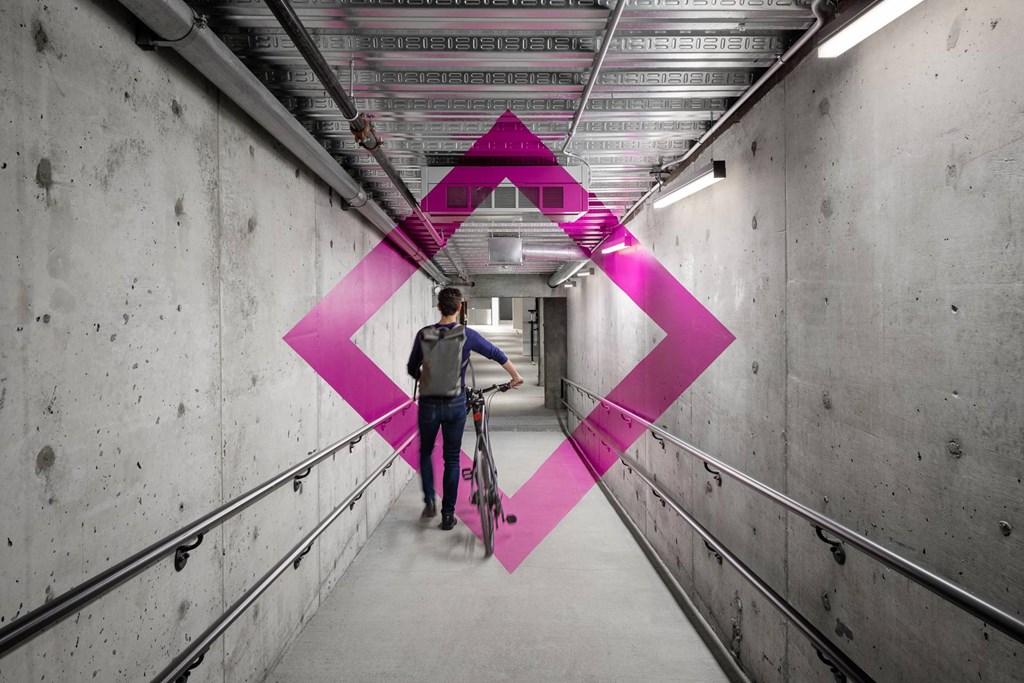 A person riding a bicycle in a tunnel with a pink diamond-shaped light.