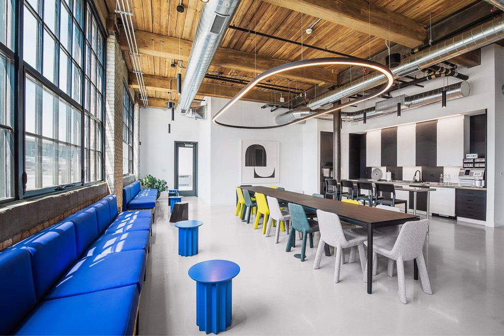 A modern open plan office with a blue sofa and a long table with chairs.