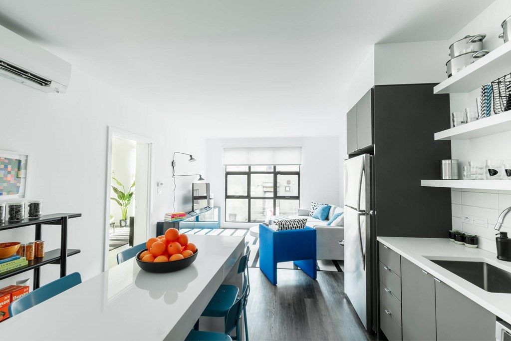 A kitchen with a white counter top and blue chairs.
