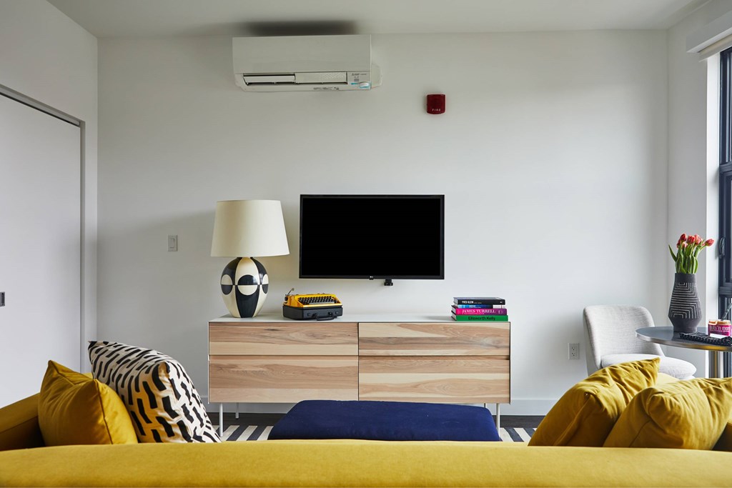 A modern bedroom with a yellow bed and a television on a wooden stand.